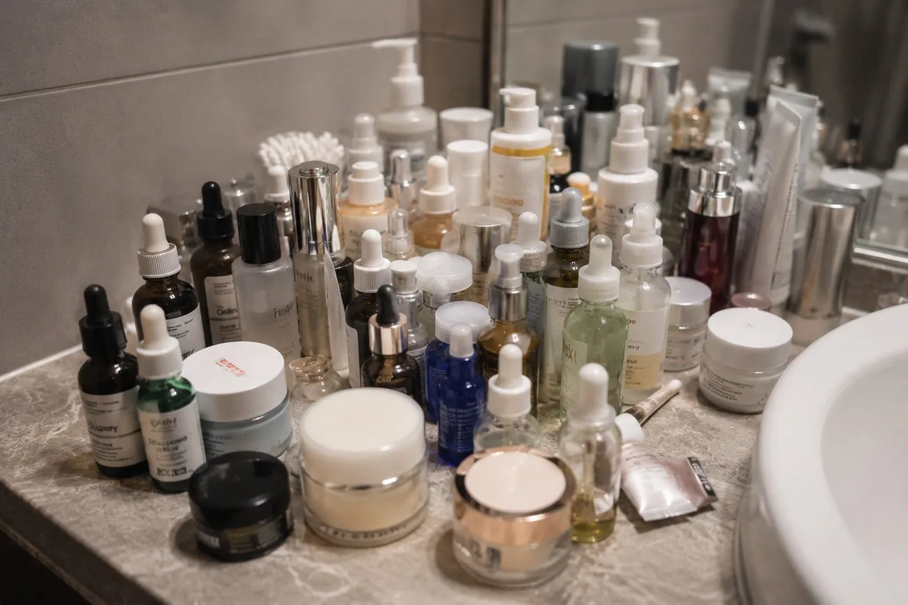 A cluttered vanity crowded with half-used serum bottles